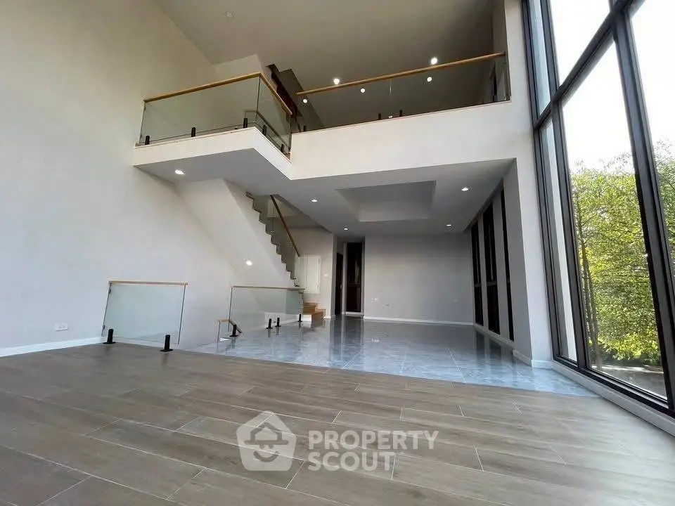 Spacious modern living room with high ceilings and large windows offering natural light and scenic views.