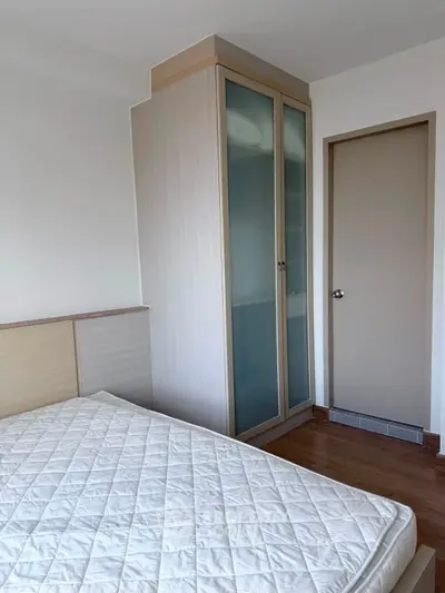 Modern bedroom with wooden flooring and built-in wardrobe, featuring a comfortable mattress.