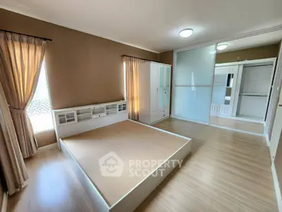 Spacious bedroom with modern design and ample natural light, featuring elegant wooden flooring and built-in wardrobe.