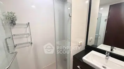 Modern bathroom with glass shower and sleek fixtures in contemporary apartment.