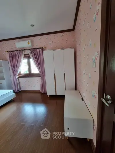 Charming bedroom with pink wallpaper, wooden flooring, and modern white furniture, perfect for a cozy retreat.