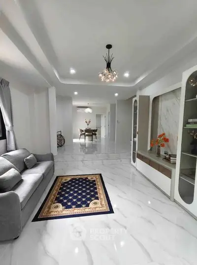 Spacious modern living room with elegant decor and open layout, featuring a plush sofa and stylish chandelier.