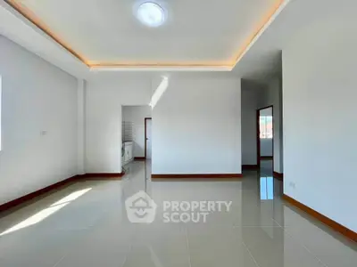 Spacious modern living room with sleek tile flooring and ambient ceiling lighting.