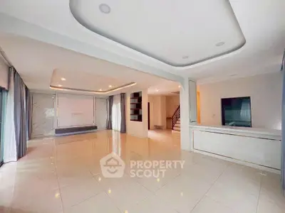 Spacious modern living room with elegant ceiling design and large windows for natural light.