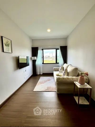 Cozy living room with elegant sofa and large window offering natural light.