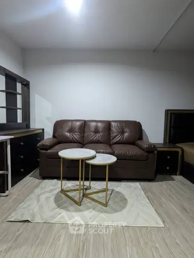 Modern living room with brown leather sofa and stylish nested tables on a chic rug.