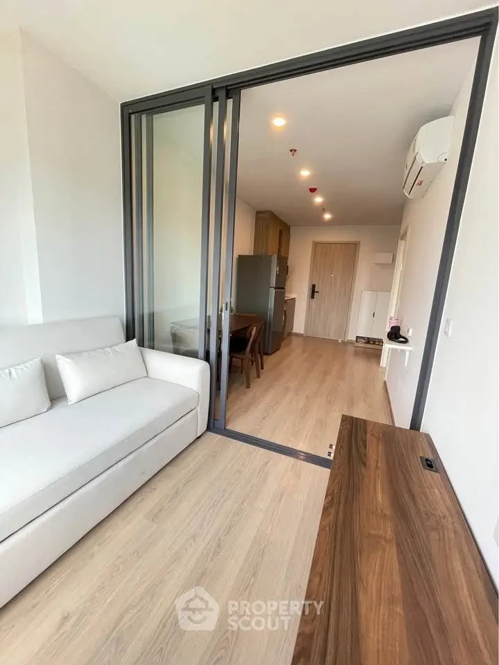 Modern open-plan living room with sliding glass doors and sleek wooden furniture