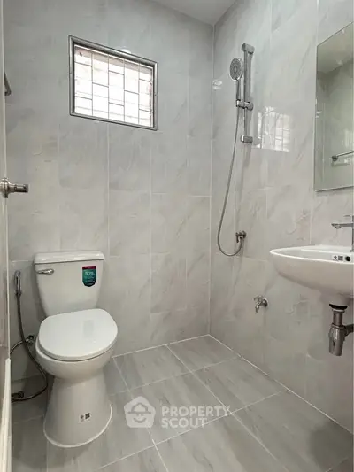 Modern bathroom with sleek fixtures and tiled walls, featuring a shower and toilet.