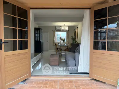 Spacious living room with open wooden doors, modern furniture, and elegant dining area.