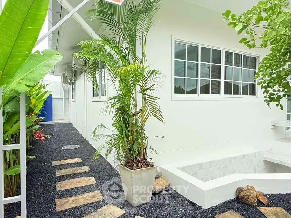 Charming exterior view of a modern home with lush greenery and stone pathway.