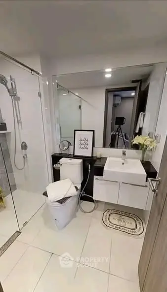 Modern bathroom with glass shower and sleek vanity in contemporary apartment.