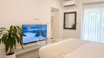 Modern bedroom with stylish decor and wall-mounted TV, featuring a cozy ambiance and natural light.