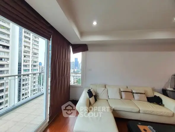 Spacious living room with modern sofa and city view balcony in high-rise apartment.