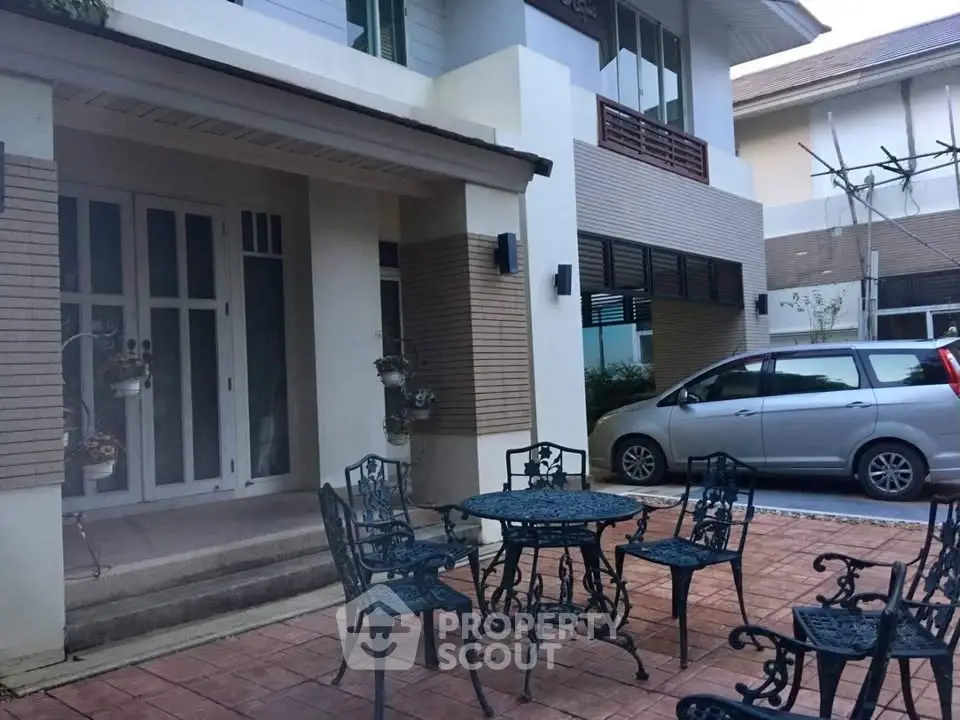 Charming residential exterior with stylish patio furniture and parked car, perfect for family gatherings.