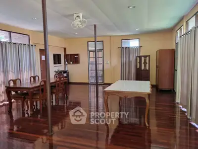 Spacious open-plan living and dining area with polished wooden floors and elegant furniture.