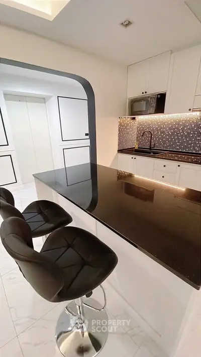 Modern kitchen with sleek black countertop and stylish bar stools
