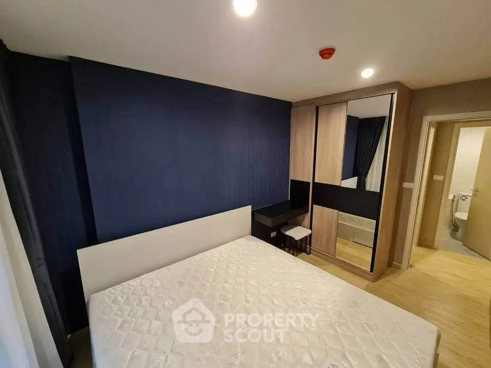 Modern bedroom with stylish blue accent wall and mirrored wardrobe