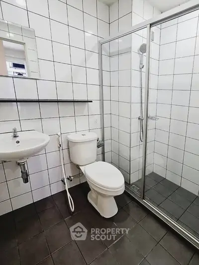 Modern bathroom with sleek white tiles and glass shower enclosure