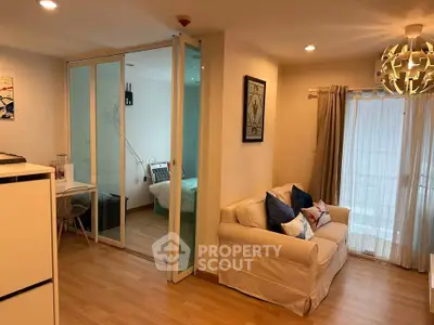 Cozy living room with sliding glass doors leading to a modern bedroom, featuring stylish decor and ample natural light.