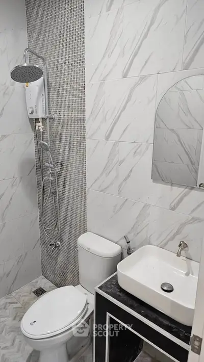 Modern bathroom with sleek fixtures and stylish tile design, featuring a shower, toilet, and sink.