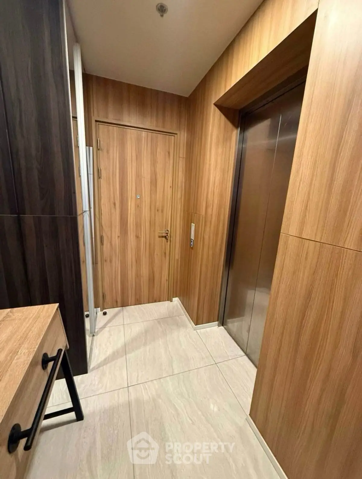Modern apartment entrance with sleek elevator and wooden paneling.