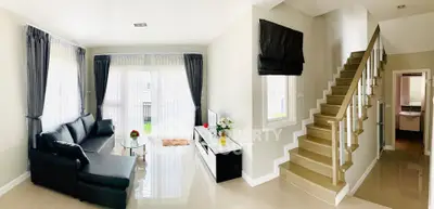 Spacious modern living room with elegant staircase and natural light.