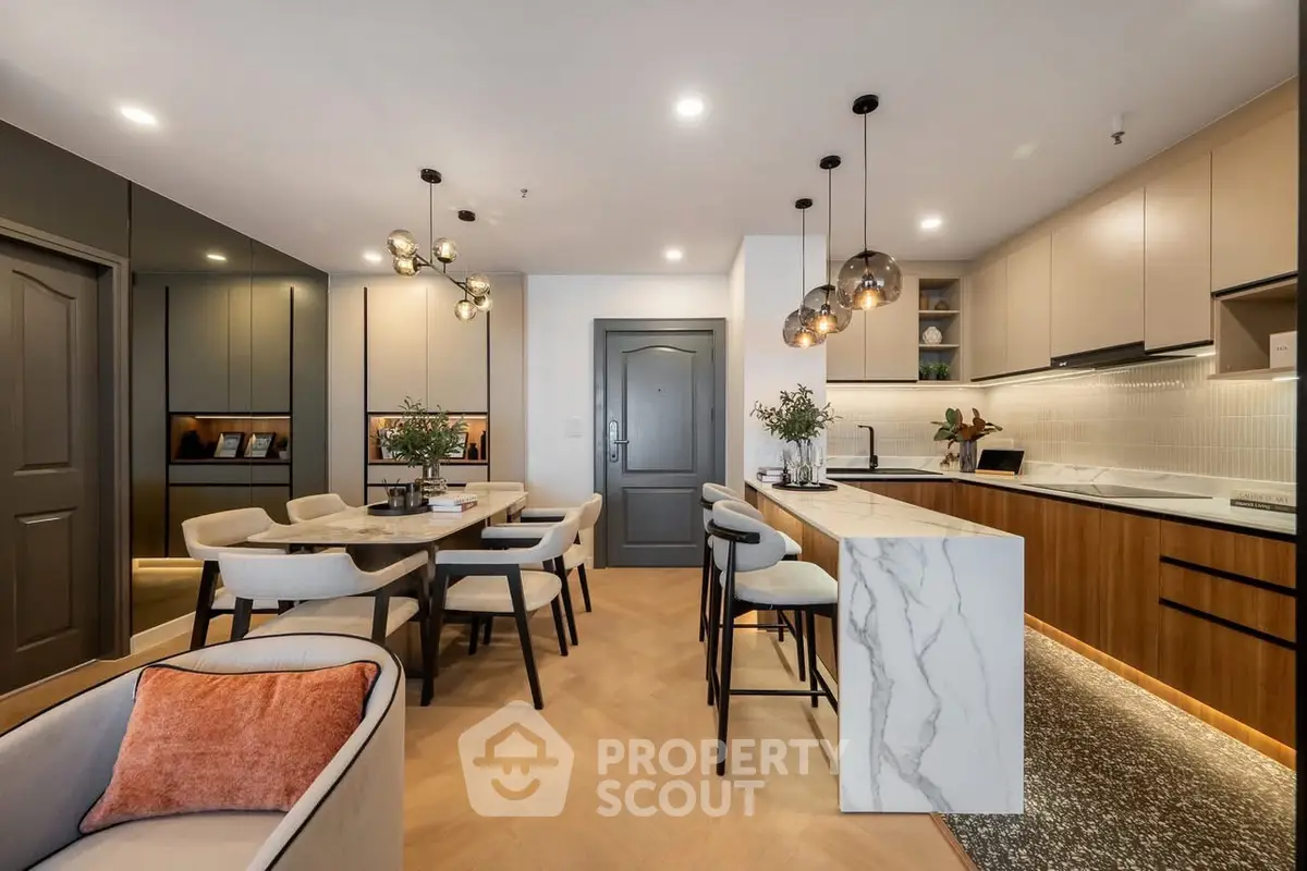 Modern open-plan kitchen and dining area with stylish lighting and marble island.