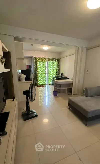 Spacious living room with modern decor and natural light, featuring a cozy sofa and stylish fan.