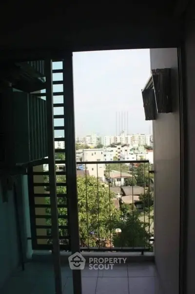 Charming balcony view overlooking urban landscape with lush greenery and distant buildings.