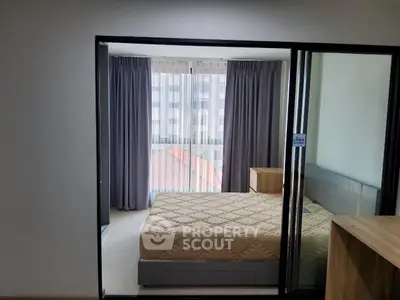 Modern bedroom with large window and stylish furnishings in a contemporary apartment.