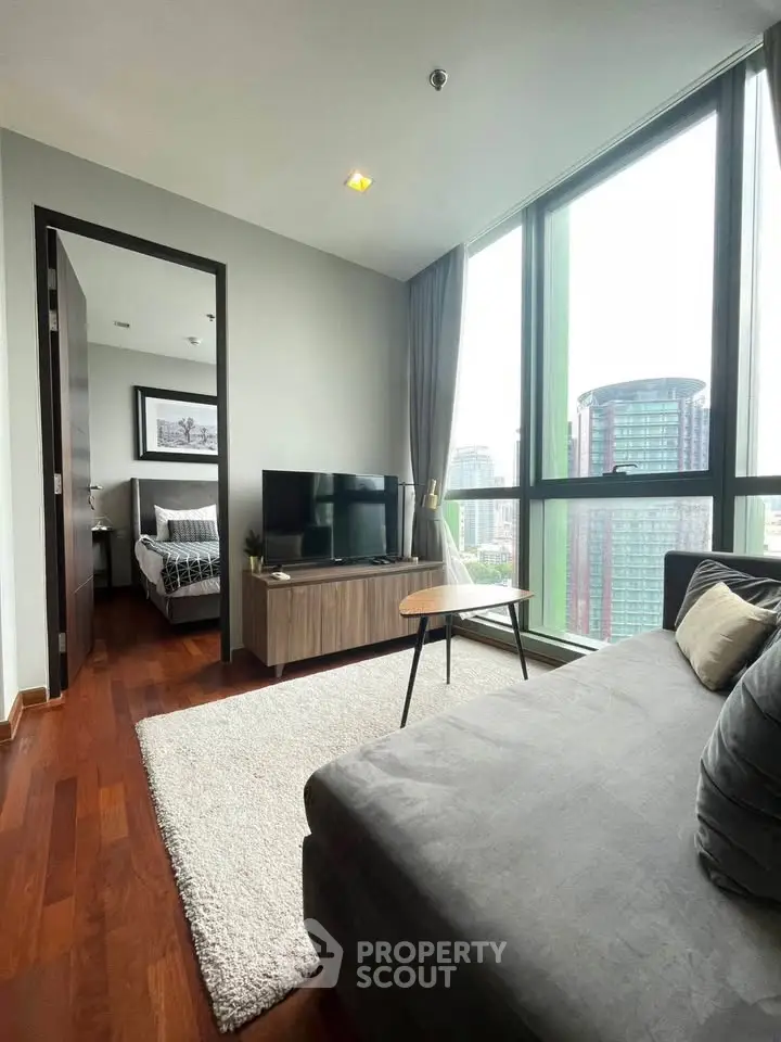 Modern living room with city view, featuring sleek furniture and large windows.