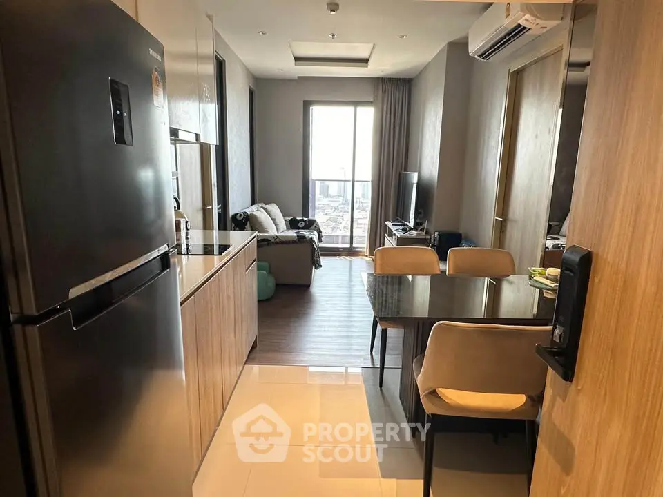 Modern apartment with sleek kitchen and cozy living area, featuring a large fridge and dining table.