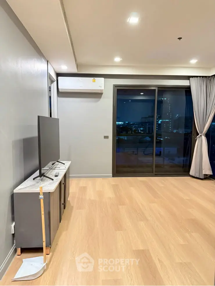 Modern living room with wooden flooring and city view from large windows.
