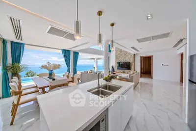 Luxurious open-plan living room with stunning ocean view and modern kitchen island.