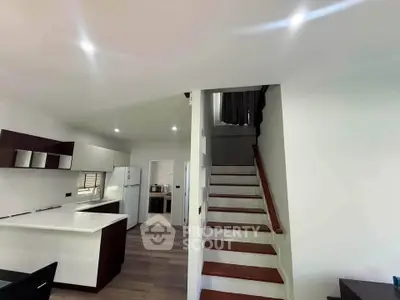 Modern kitchen with sleek design and staircase leading to upper floor in a stylish home.
