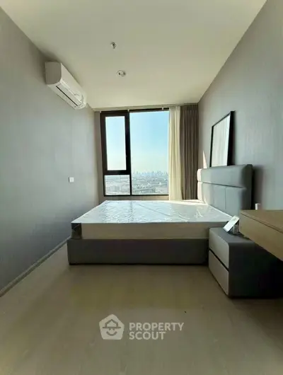 Modern bedroom with city view, featuring sleek furniture and large window.