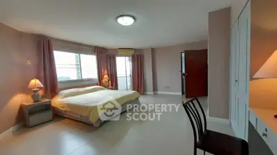 Spacious bedroom with large windows and cozy lighting in modern apartment.