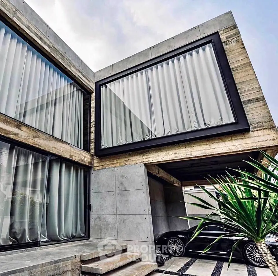 Modern architectural home with sleek concrete design and luxury car in driveway.
