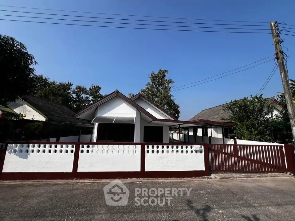 Charming single-story home with a white picket fence and lush greenery, perfect for serene living.