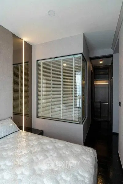 Modern bedroom with sleek design and large window, featuring stylish blinds and elegant lighting.