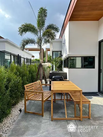 Modern outdoor patio with wooden furniture and lush greenery