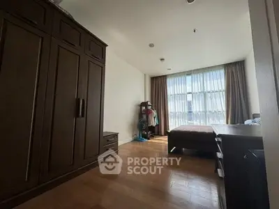 Spacious bedroom with large wardrobe and natural light from floor-to-ceiling windows.