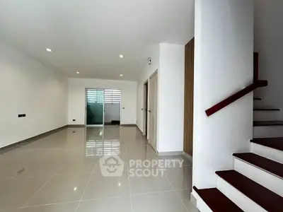 Spacious modern living room with sleek tile flooring and staircase, perfect for contemporary living.