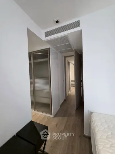 Modern bedroom with sleek design and wooden flooring, featuring a built-in wardrobe and minimalist decor.