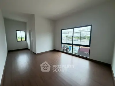 Spacious empty room with large windows and wooden flooring, perfect for customization.