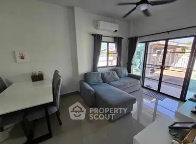 Modern living room with cozy sofa and dining area, featuring large windows and air conditioning.
