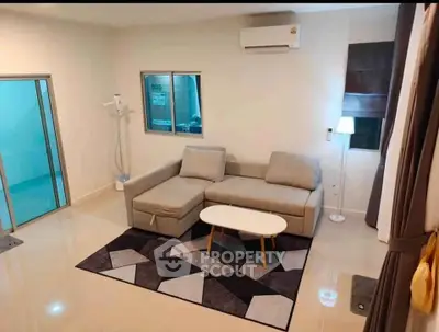 Modern living room with stylish sofa and geometric rug, featuring air conditioning and ambient lighting.