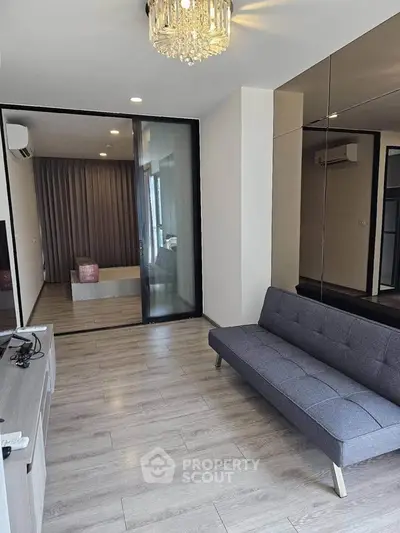 Modern living room with sleek design and glass partition leading to bedroom, featuring stylish sofa and elegant lighting.
