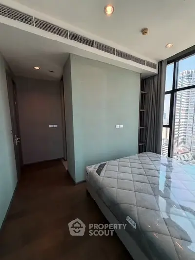 Modern bedroom with large windows offering city views in a high-rise apartment.