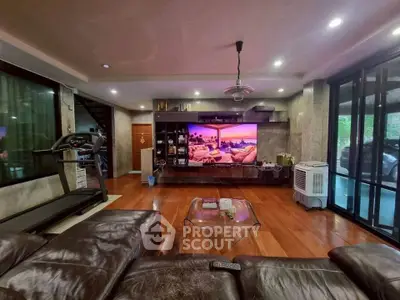 Spacious living room with modern decor and large TV, perfect for entertainment.